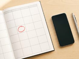 Kalender mit markiertem Termin neben Smartphone und Kugelschreiber
