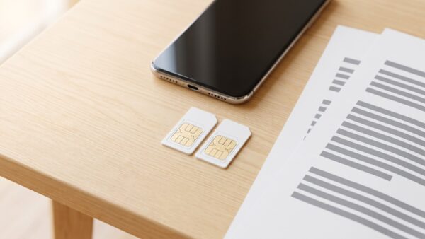 wechsel simkarten Zwei SIM-Karten und ein Smartphone liegen auf einem Schreibtisch neben Unterlagen