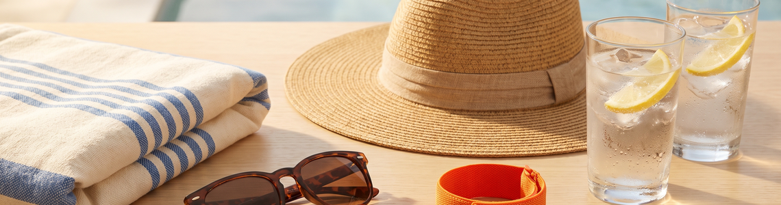 All-Inclusive-Urlaub am Pool: Strandtuch, Sonnenhut, Armband und kalte Getränke
