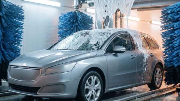 Auto in der Waschstraße mit Schaum und rotierenden Bürsten