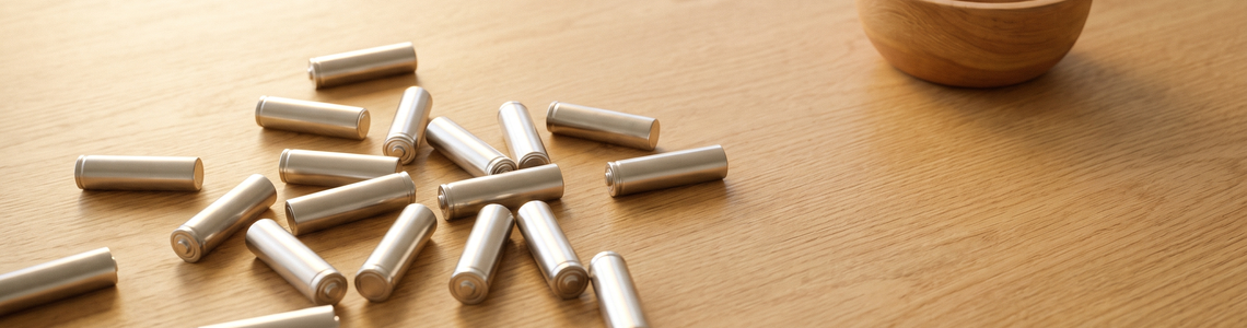 Zylindrische Batterien ohne Aufdruck neben einer Holzschale