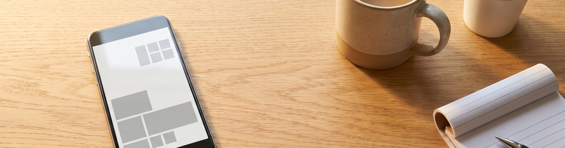 Aufgeräumter Startbildschirm auf dem Smartphone neben Kaffee und Notizblock
