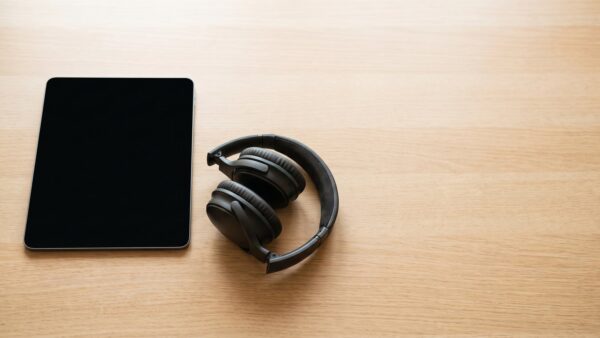 Abgelegtes Tablet mit schwarzem Bildschirm neben Kopfhoerern