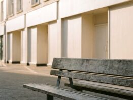 Leere Fußgängerzone mit heller Ladenzeile und Holzbank