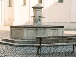 Schlichter Steinbrunnen mit leerer Holzbank davor