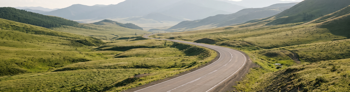 Leere Autobahn durch eine grüne hügelige Berglandschaft