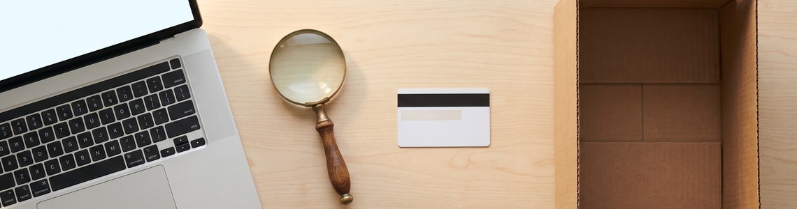 Fake-Shops erkennen Pruefung mit Lupe Laptop und Bankkarte