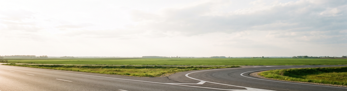 Leere Autobahnausfahrt vor flachem grünem Land