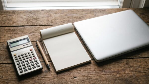 finanz rechnen Taschenrechner, Notizblock und Münzen auf einem Tisch