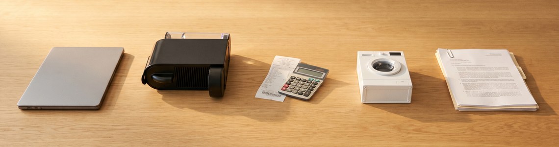 Garantieverlängerung für Elektrogeräte: Waschmaschine, Notebook und Kaffeevollautomat mit Kassenbon auf einem Holztisch