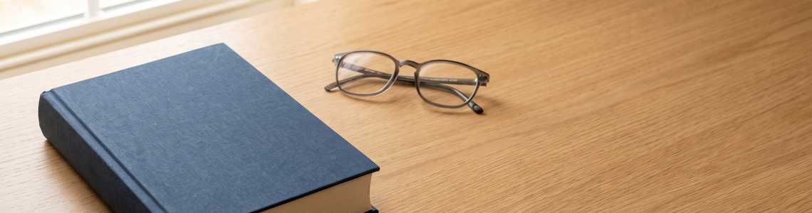 Geschlossenes Buch mit blauem Leineneinband auf einem hellen Schreibtisch