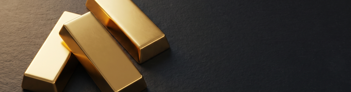 Drei glatte goldfarbene Metallbarren ohne Prägung auf dunklem Schiefer