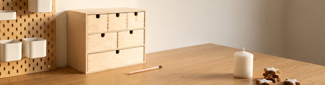 Lochplatte, Mini-Kommode und Kerze auf einem hellen Holztisch