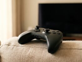 Neutraler Controller auf einem Sofakissen vor dunklem Fernseher