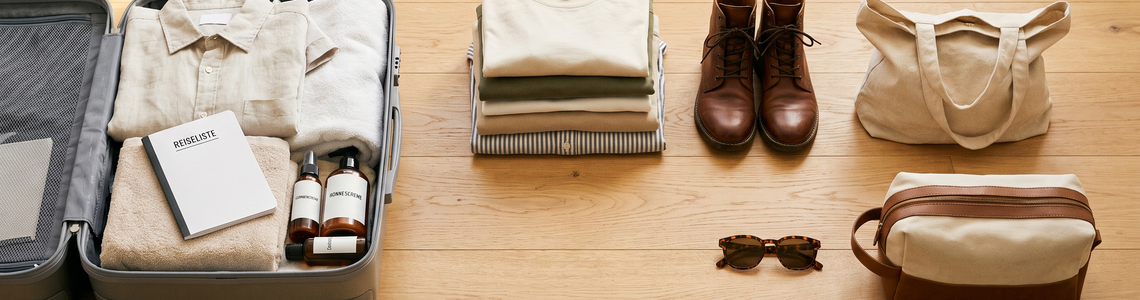 Halb gepackter Koffer mit Kleidung und Zubehör für die Kreuzfahrt