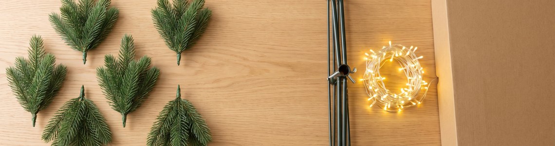 Kuenstlicher Weihnachtsbaum: Zweige, Staender und Lichterkette auf Holztisch