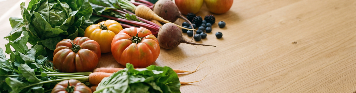 Frisches unverpacktes Gemüse und Obst auf einer Holzfläche