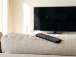 Fernbedienung auf dem Sofa vor einem dunklen Fernsehbildschirm