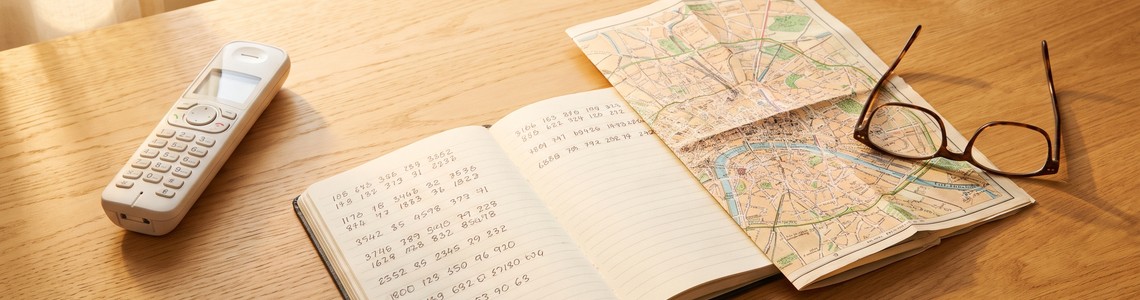 Telefon, Notizblock und Stadtplan auf einem Schreibtisch