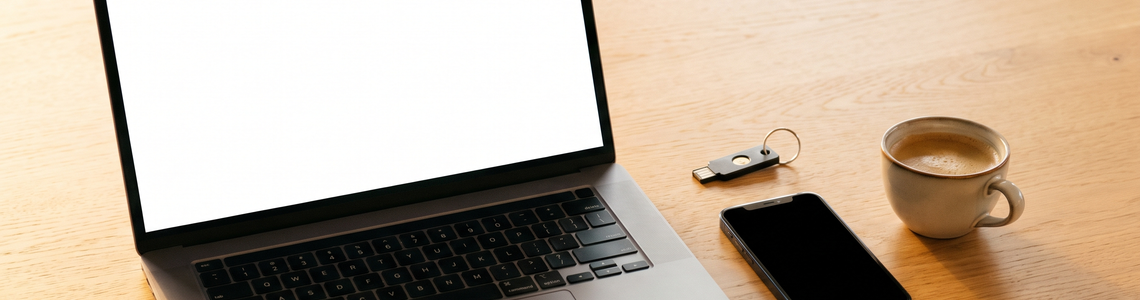 Passkeys: Laptop, Smartphone und Sicherheitsschlüssel auf dem Schreibtisch