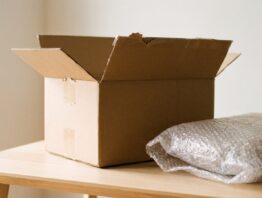 Geoeffneter Versandkarton mit Polstermaterial auf hellem Holztisch