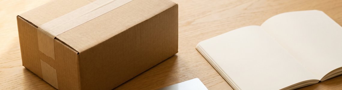Paket, Bankkarte und Notizbuch auf einem hellen Schreibtisch