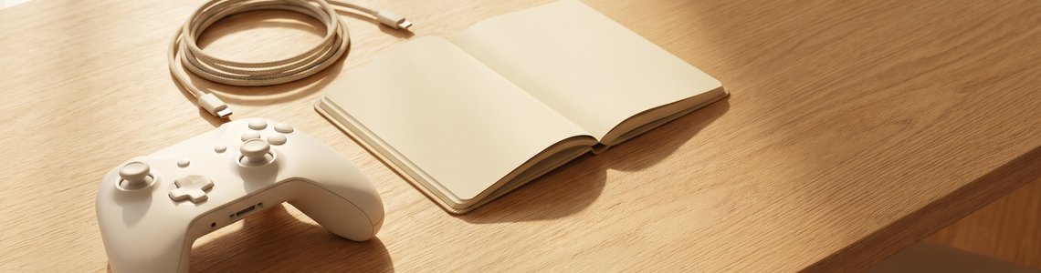 Weisser Gaming-Controller mit Kabel und Notizbuch auf hellem Holztisch