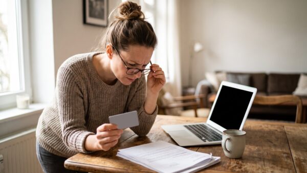 ppk inline4 Frau prüft skeptisch das Kleingedruckte eines Prepaid-Kreditkarten-Angebots am Küchentisch