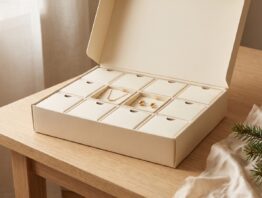 Geöffneter Schmuck-Adventskalender mit Goldkette und Ohrsteckern auf einem Holztisch