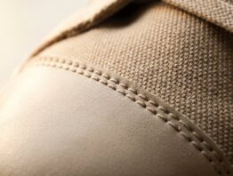 Nahaufnahme von Textilgewebe und Lederkappe eines Sneakers