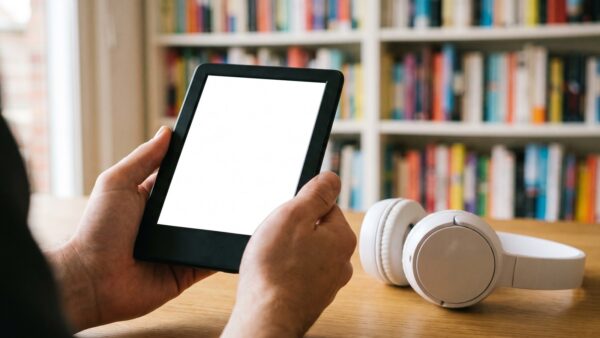 thalia gutschein ebook hoerbuch E-Reader und Kopfhoerer vor Buecherregal fuer Thalia Gutschein einloesen