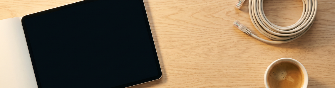 Notebook mit dunklem Bildschirm neben Netzwerkkabel und Kaffee