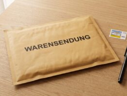 Warensendung Umschlag mit Aufschrift und Briefmarke auf Schreibtisch