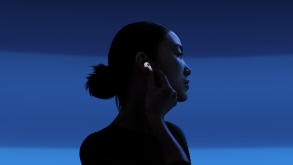 airpods 5 apple 4 Person setzt sich einen AirPod 5 ins Ohr, blauer Hintergrund