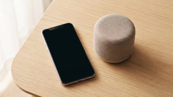 alexa umbenennen bild 2 Smartphone mit dunklem Bildschirm neben einem kleinen Lautsprecher