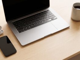 amazon music login bild 1 Laptop, Smartphone mit dunklem Display, Ohrhörer und Kaffeetasse auf einem hellen Schreibtisch