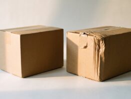 Ein makelloser und ein eingedrückter Versandkarton nebeneinander