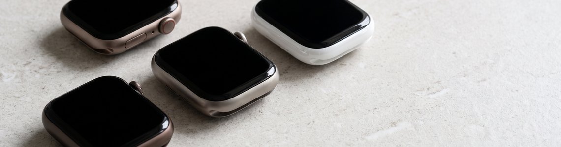 Drei Smartwatches in Aluminium, Titan und Keramik auf heller Steinfläche