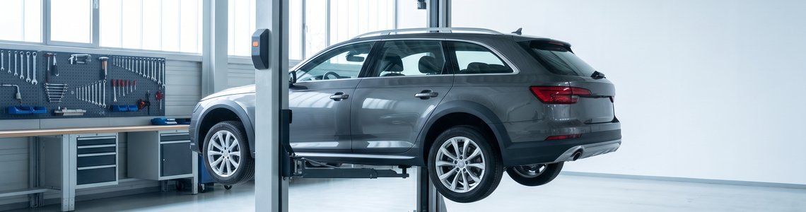 Aufgeräumte Kfz-Werkstatt mit einem grauen Kombi auf der Hebebühne