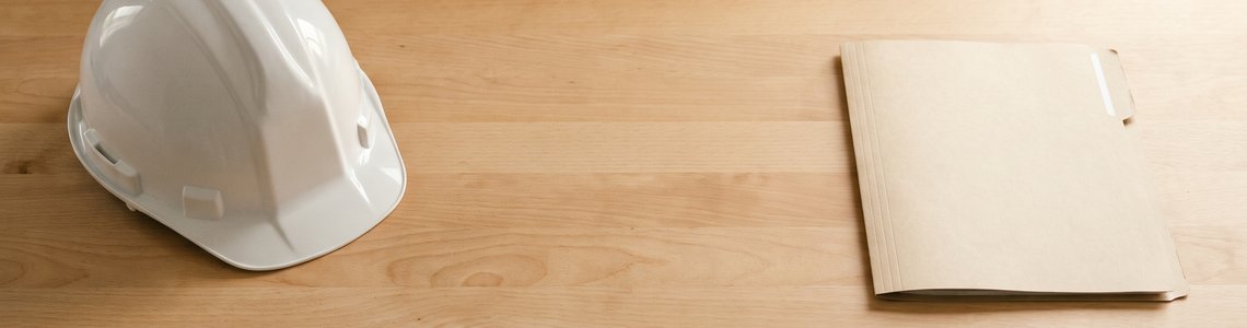 Aufgeräumte Werkbank mit unbeschriftetem Schutzhelm und leerem Ordner im Tageslicht