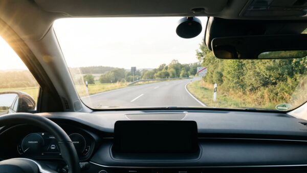 blitzerwarner rechtslage Blick durch die Windschutzscheibe auf eine Landstraße mit kleinem Warngerät an der Scheibe