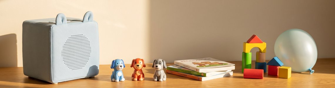 Kinder-Hörbox mit drei sitzenden Hunde-Hörfiguren auf einem Holztisch im Kinderzimmer