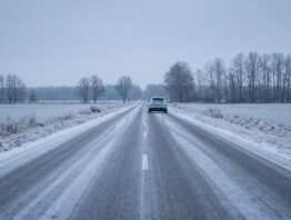bmw ix3 bild 1 Leere Landstraße bei Raureif mit einem hellen Elektroauto in der Ferne