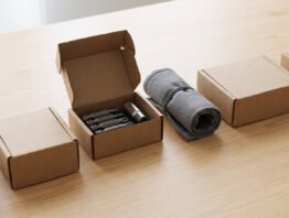 Unbedruckte Pappschachteln auf einem Holztisch, eine davon geöffnet mit Bits und Steckschlüssel