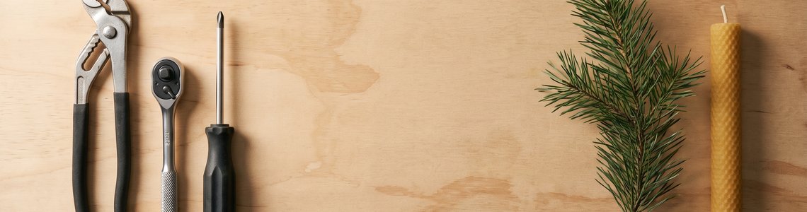 Handwerkzeuge auf einer Werkbank neben einem Tannenzweig und einer Kerze