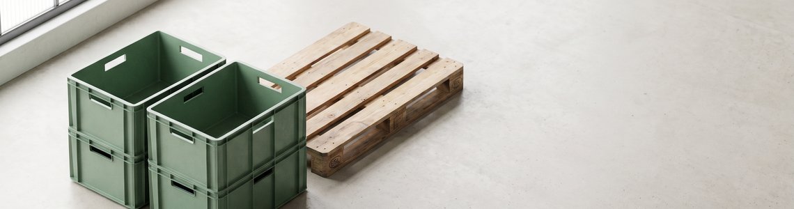 Leere Stapelkisten und Holzpalette in einer hellen Lagerhalle