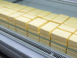 Kühlregal im Supermarkt mit unbedruckten Butterpäckchen und leerer Regalschiene
