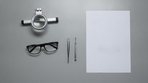 datenbrille kaufen bild 3 Zerlegtes Brillengestell auf einer Werkbank neben Pinzette, Schraubendreher und Lupe