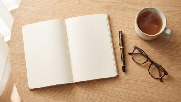 Leeres Notizbuch mit Füller, Lesebrille und Teetasse