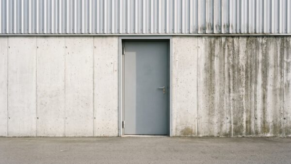 Schlichte graue Industrietür in einer Beton- und Wellblechfassade